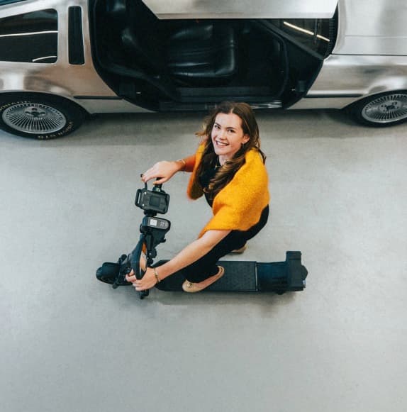 Van bovenaf: een medewerker zit op een goedgekeurde e-step naast een geopende autodeur.